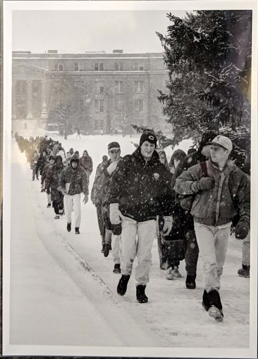 A large group of students walking along the sidewalk on central campus that runs from Curtiss Hall to Beardshear Hall in the snow, 1994.