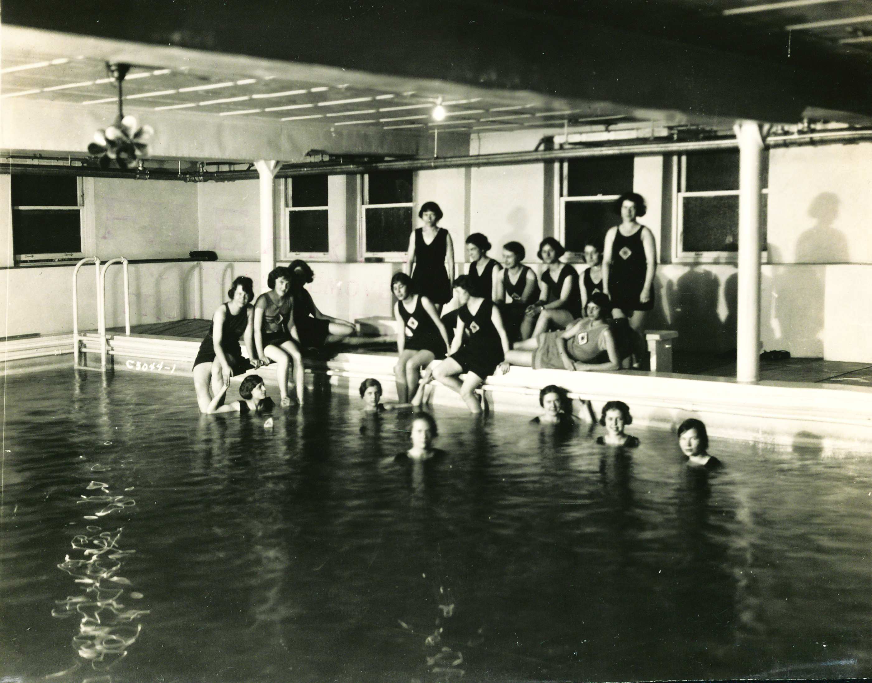 about a dozen young women in 1920s bathing costumes in a pool